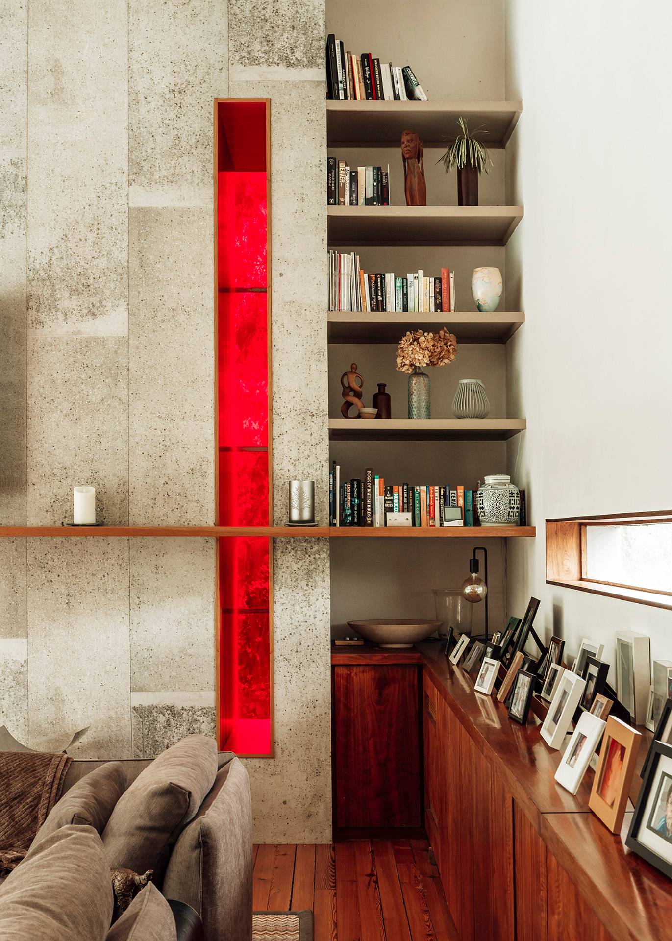 Detailed architectural view of a mid-century built-in bookshelf unit framed by textured stonework and a vibrant red glass insert, Love Locations BR1.
