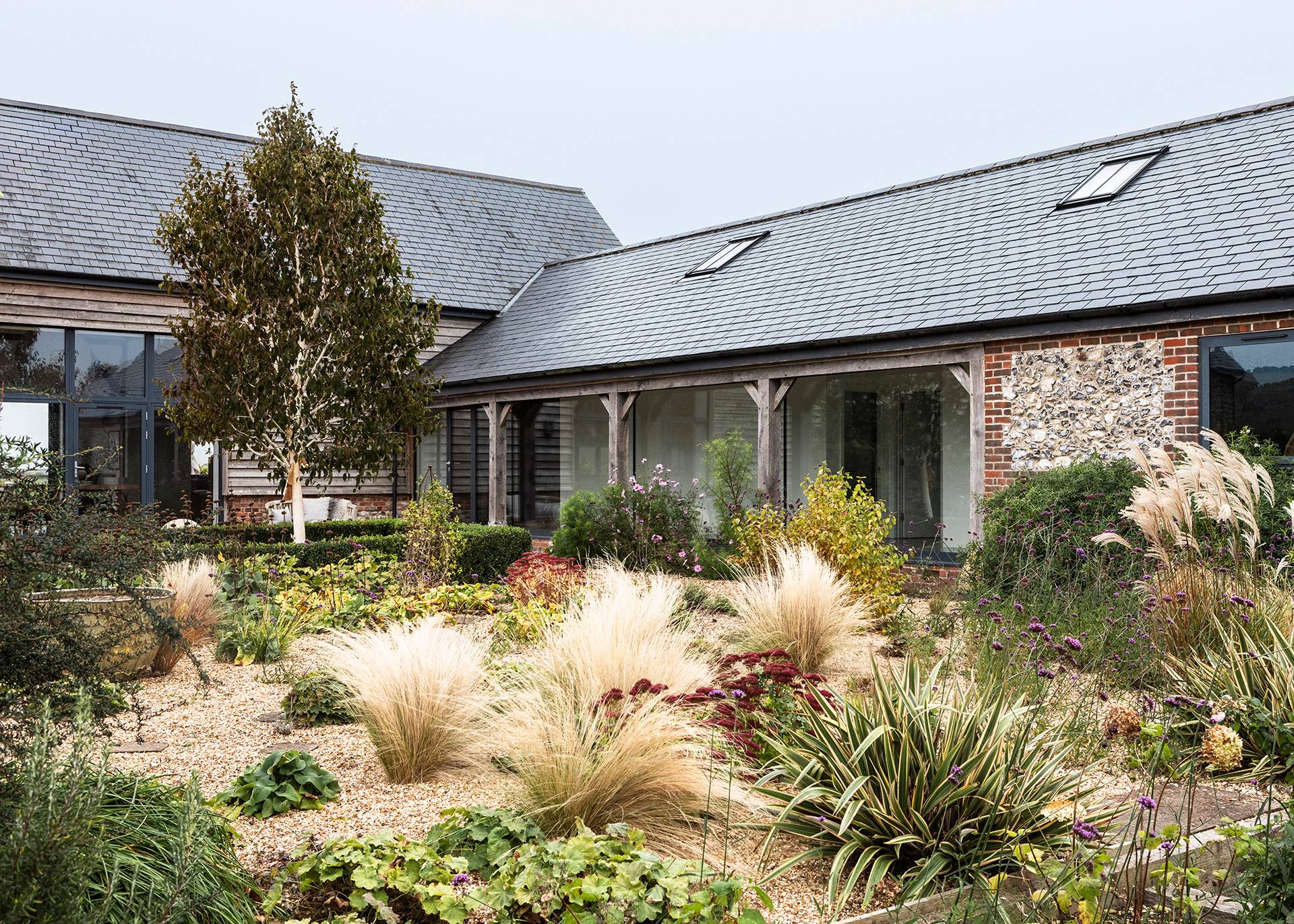 Courtyard garden view looking toward timber-clad barn buildings and stone gravel pathways, Love Locations SN8.