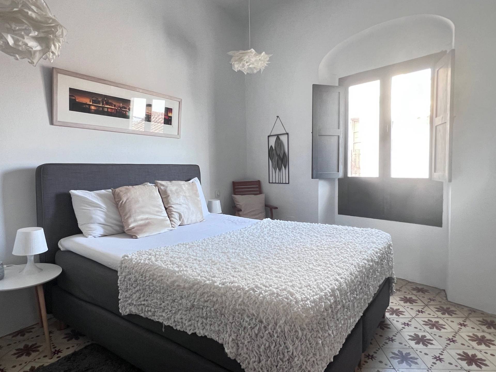 Minimalist bedroom with dark grey headboard and traditional Spanish window shutters in Jimena de la Frontera through Love Locations.