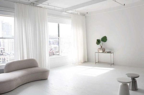 Sunlit studio window corner in New York, NY 10011 showing white sheer curtains, a minimalist armchair, and polished floors, perfect for lifestyle brand advertising, Love Locations.