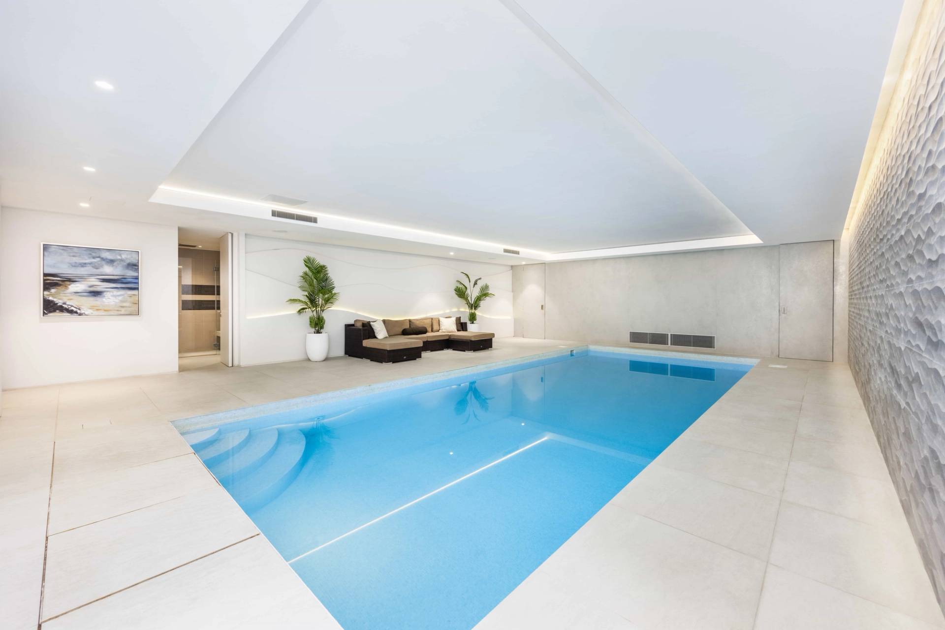 Luxury indoor swimming pool shoot location in Radlett, WD7 featuring blue tiled pool, white lounge seating, and LED rim lighting, Love Locations.