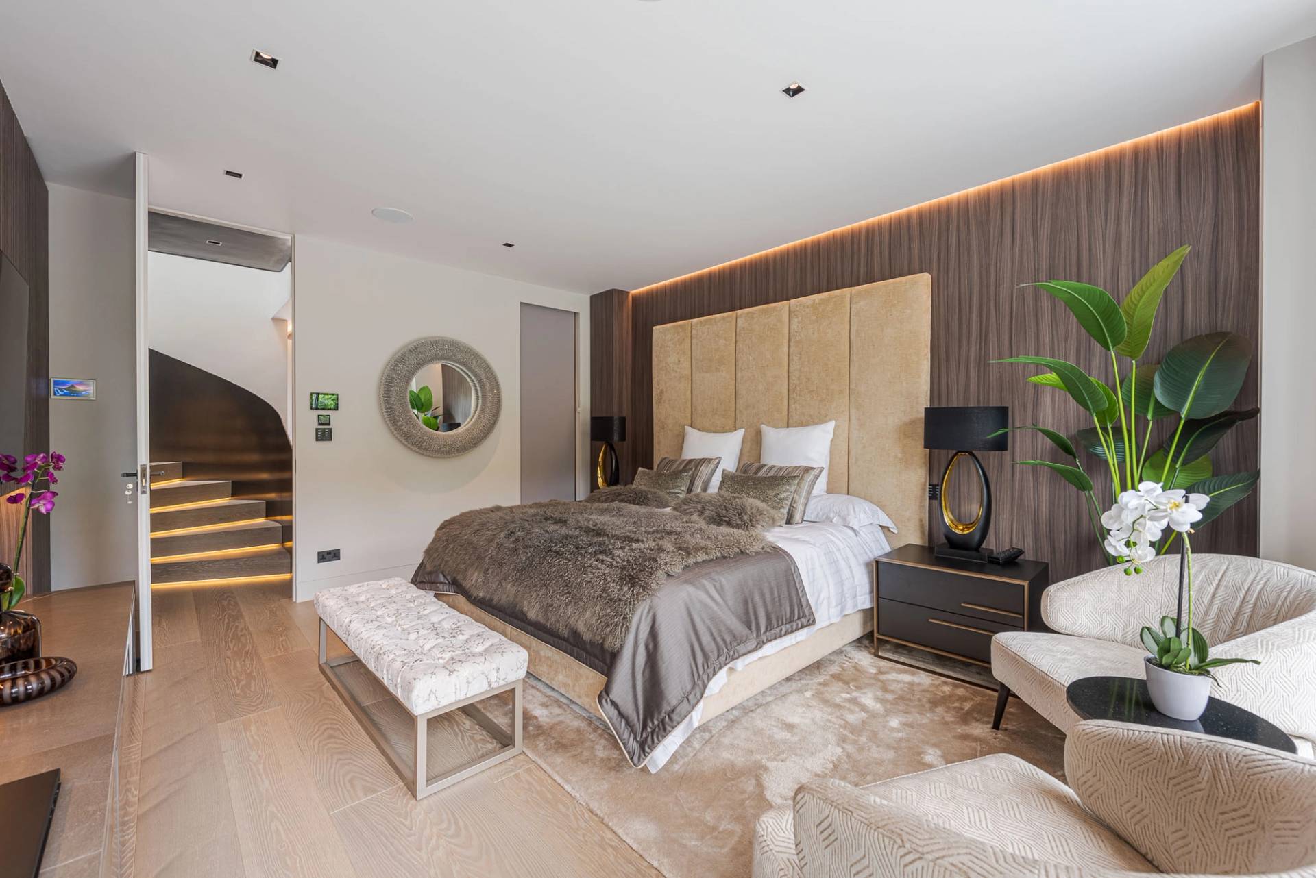 Master bedroom suite featuring a beige tufted headboard, wooden wall paneling, and neutral carpets, Love Locations SW11.