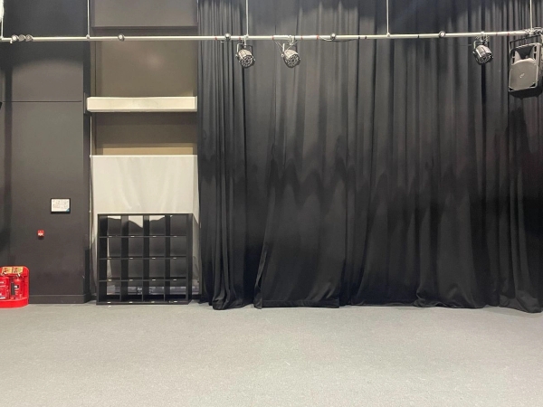 Love Locations black box drama studio RG30: Adaptable performing arts space featuring full-length black blackout curtains and an industrial grid ceiling, perfect for rehearsal scenes and independent film sets.