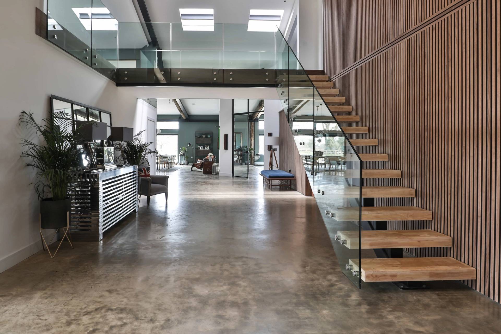Floating cantilevered wooden stairs with glass balustrade set against wood slatted feature walls, Love Locations CV23.