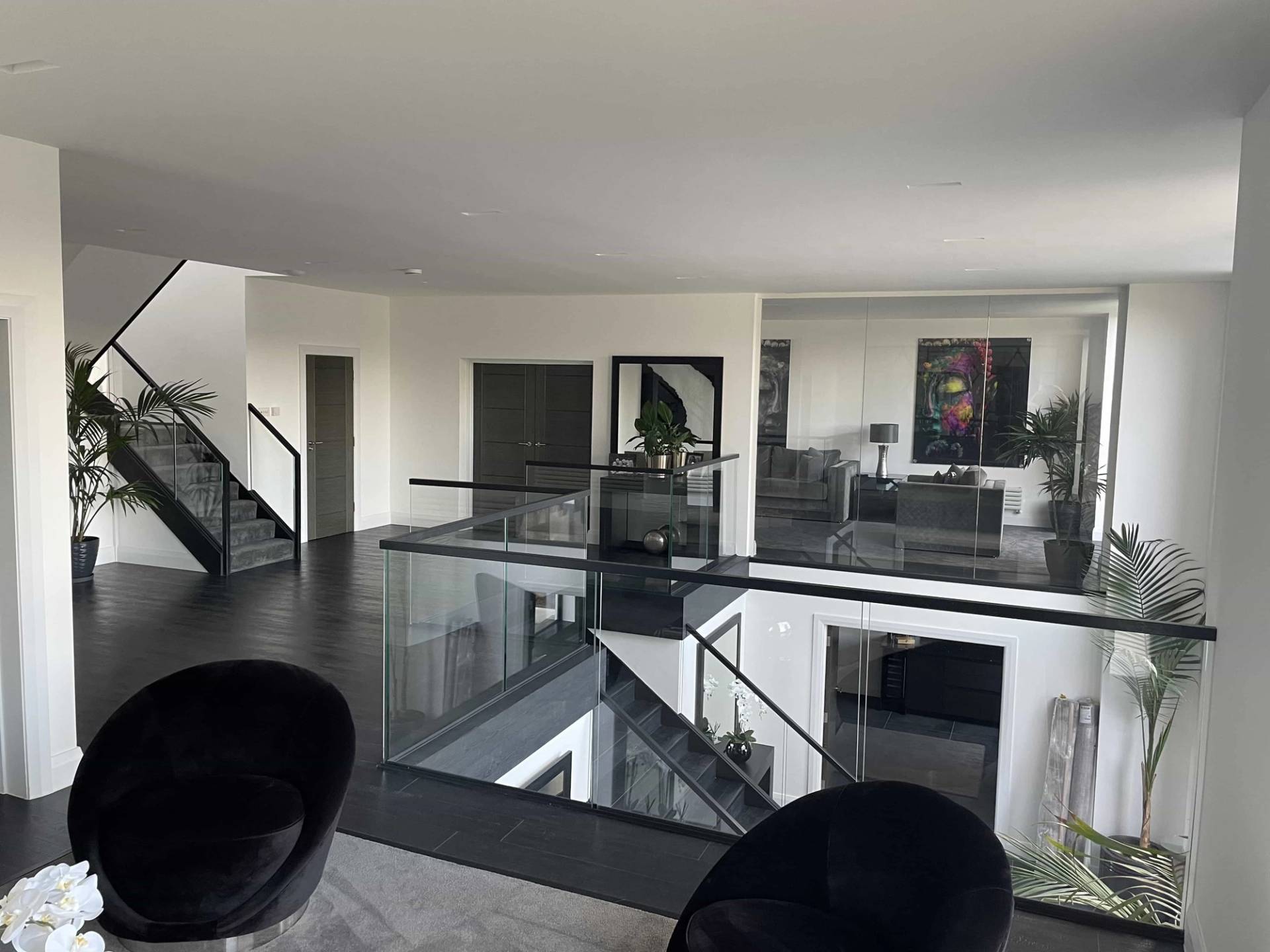 Spacious mezzanine hallway with black timber flooring, glass balustrades, and dark velvet seating, perfect for fashion editorial shoots, Love Locations IG10.