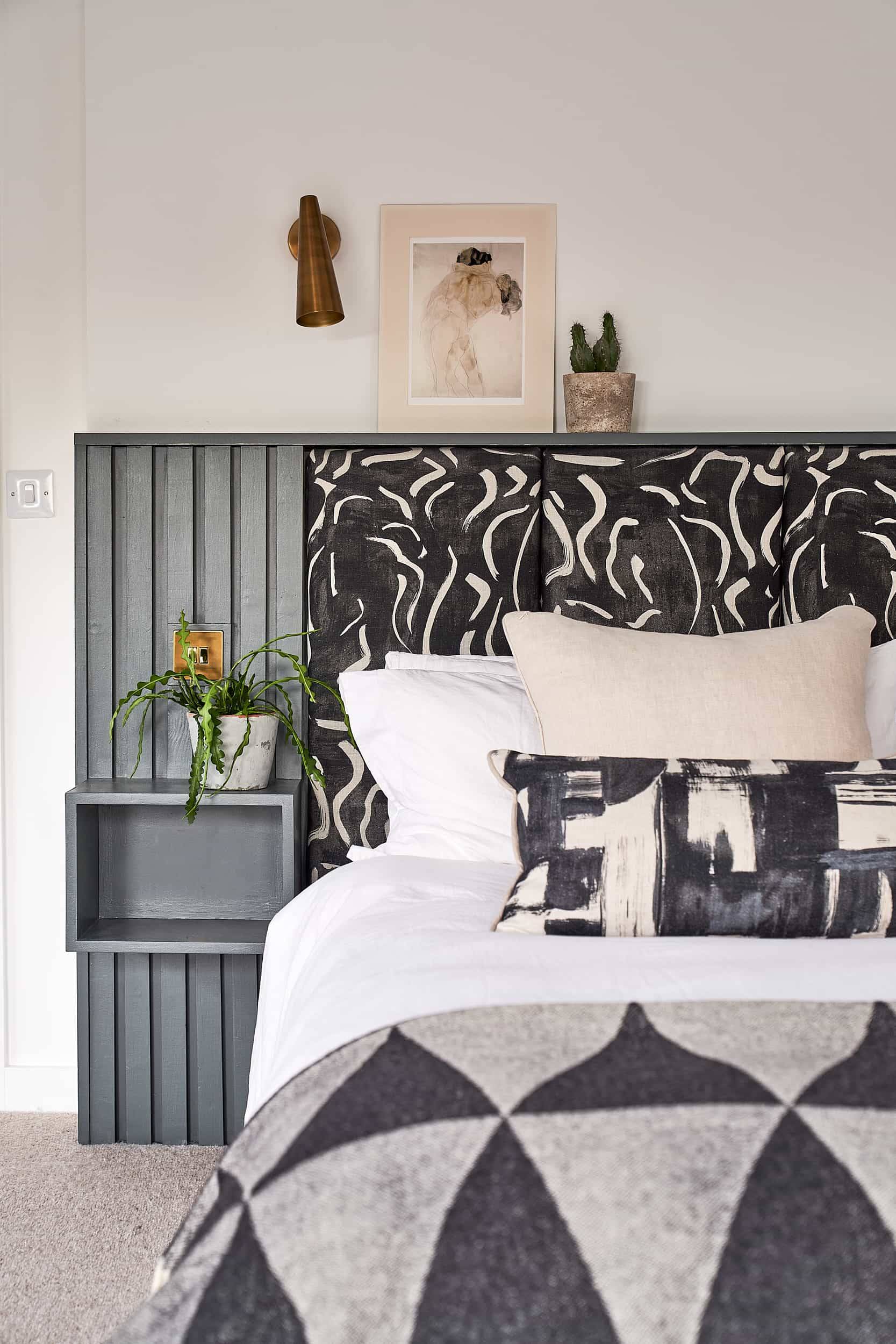 Master bed detail featuring a monochrome patterned headboard, grey panelling, and white bed linen, Love Locations IP30.