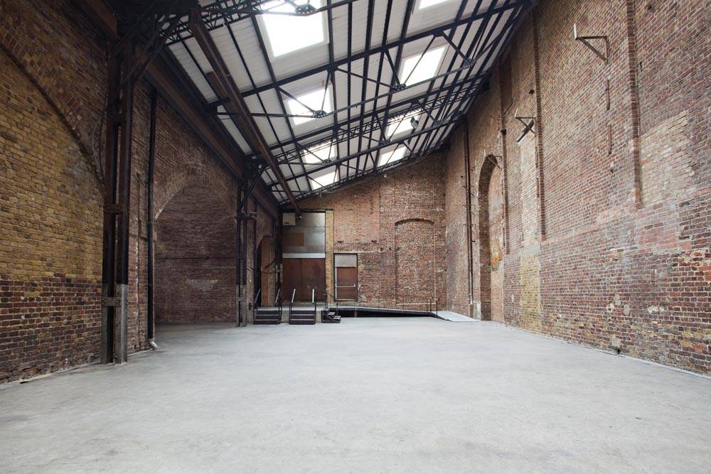 Skylit brick warehouse event space with industrial steel ceiling framing and raw brickwork in Hackney EC2A via Love Locations.