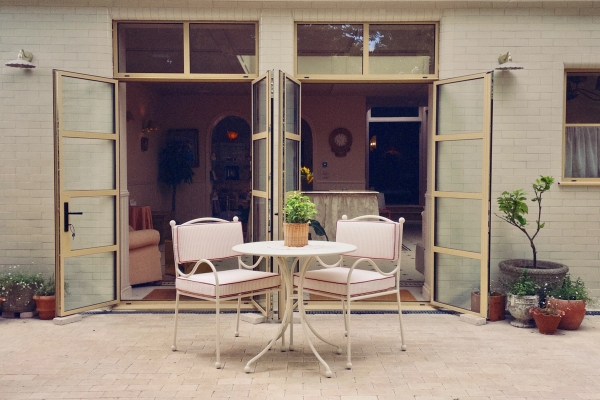 Intimate courtyard patio dining setup with matching pink-trimmed bistro chairs and table, perfect for garden furniture lookbooks, Love Locations.