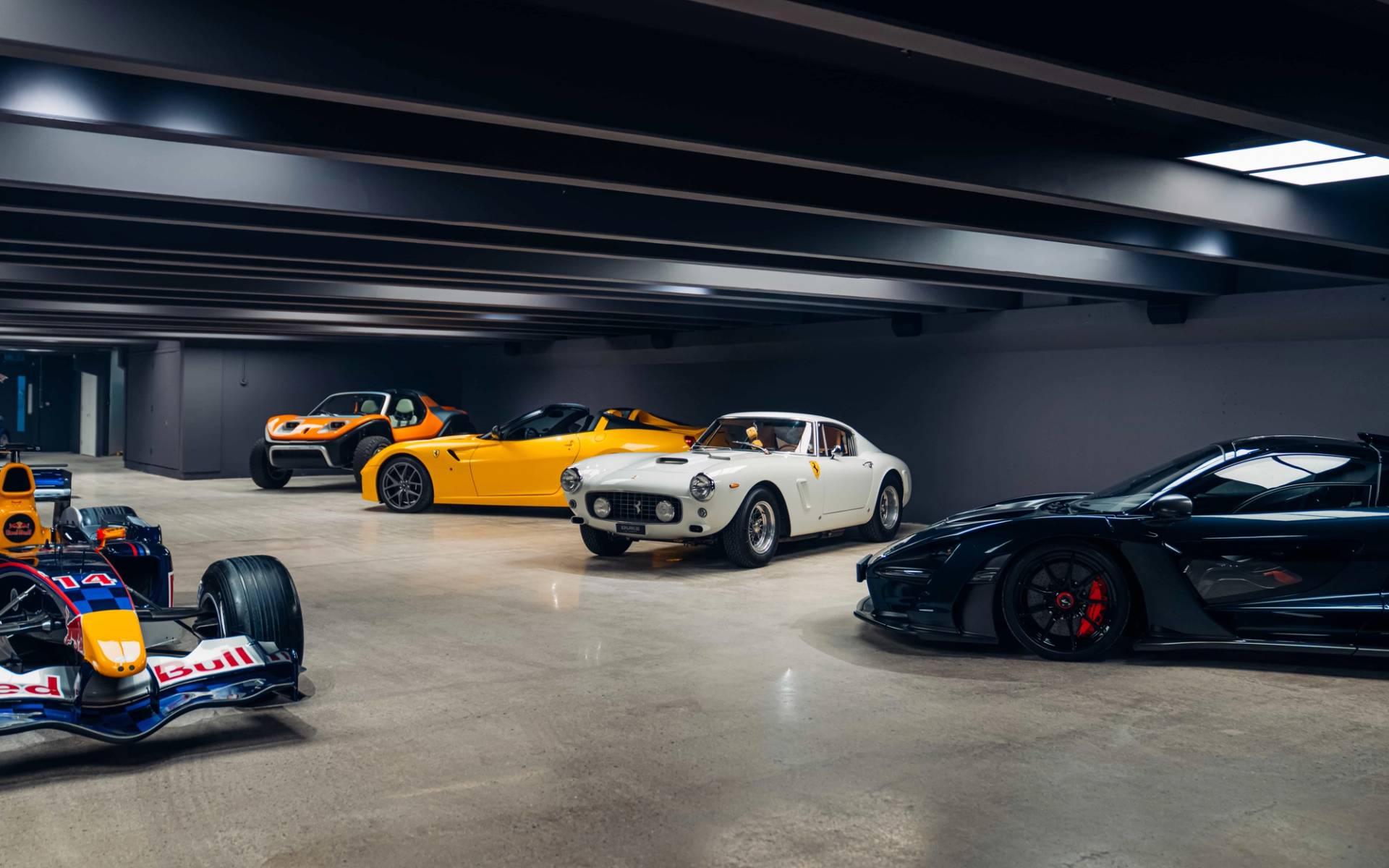 Multi-car display including a white classic sports car inside a brutalist concrete basement venue from Love Locations.
