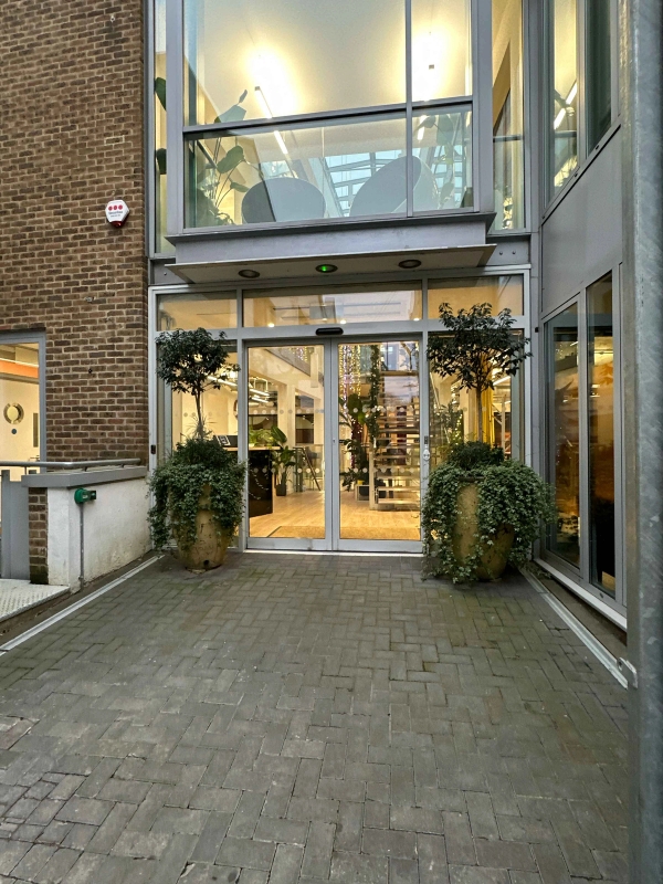 Inner courtyard at Swan Yard with smooth cobblestones, glass façade, and modern glass entrance doors leading into the building.