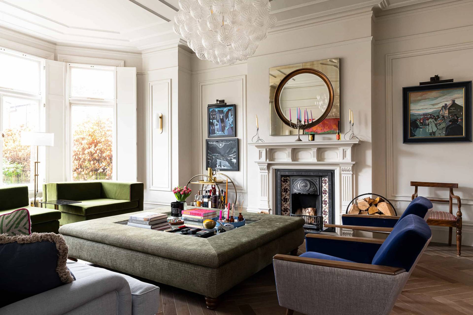 Spacious double drawing room featuring an oversized button-tufted ottoman coffee table, period fireplace, and green armchairs in Queens Park, NW6, ideal for homeware lookbooks, Love Locations.