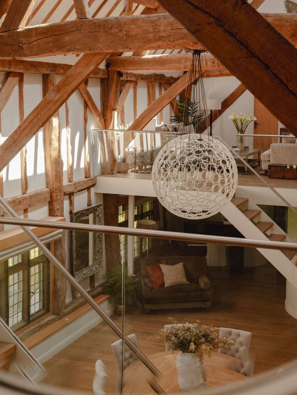 Mezzanine balcony view looking through an orb chandelier over a double-height converted barn room, ideal for creative photography angles, Love Locations RG9.