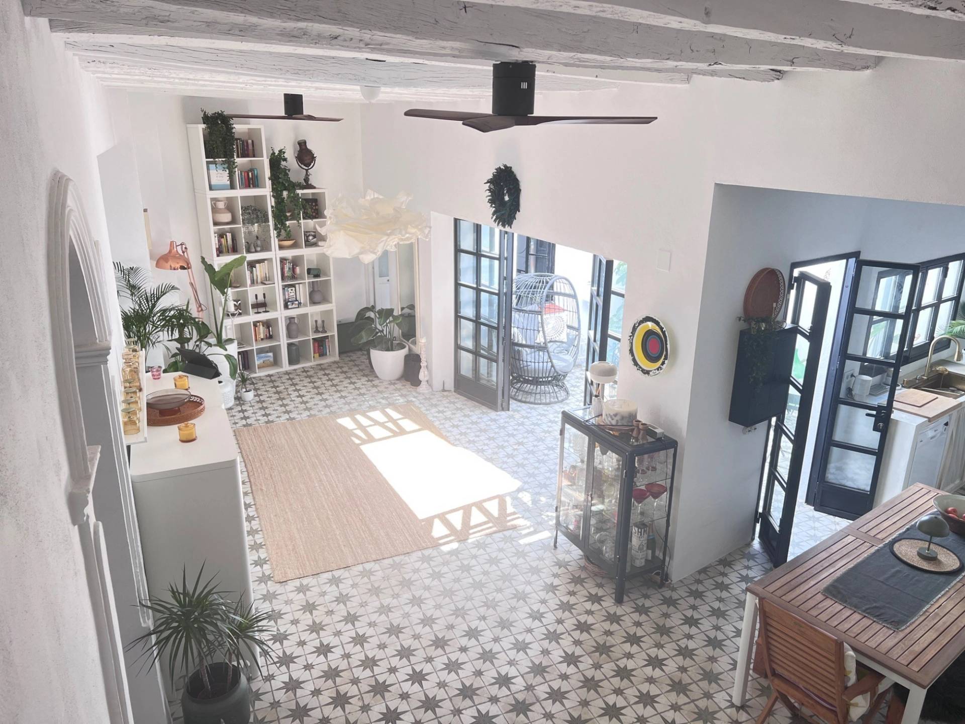 Aerial view of an open-plan kitchen and dining space with ceiling fan and patterned Andalucian tiles in Jimena de la Frontera by Love Locations.