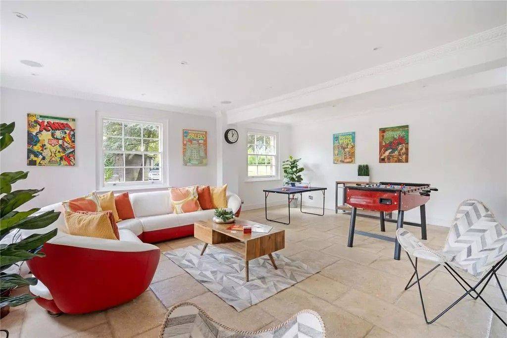 Light-filled family games room with flagstone floors, colourful sofas, and table football in an Georgian Berkshire house by Love Locations.
