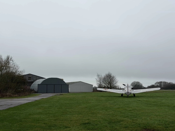 Open airfield perimeter view showing classic hangars and parked aircraft in Corby, NN17, suitable for action film backdrops via Love Locations.