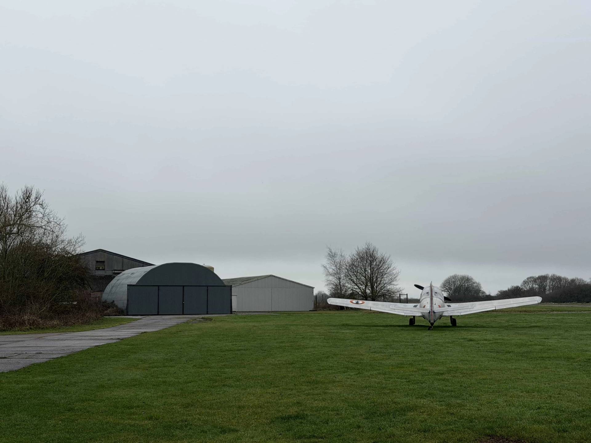Open airfield perimeter view showing classic hangars and parked aircraft in Corby, NN17, suitable for action film backdrops via Love Locations.