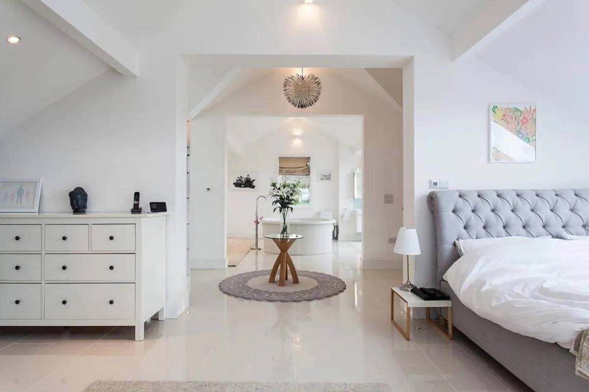 Light-filled master bedroom suite photoshoot location in Stockport SK6 via Love Locations, featuring polished tiled floors and open access to a luxury bathroom.