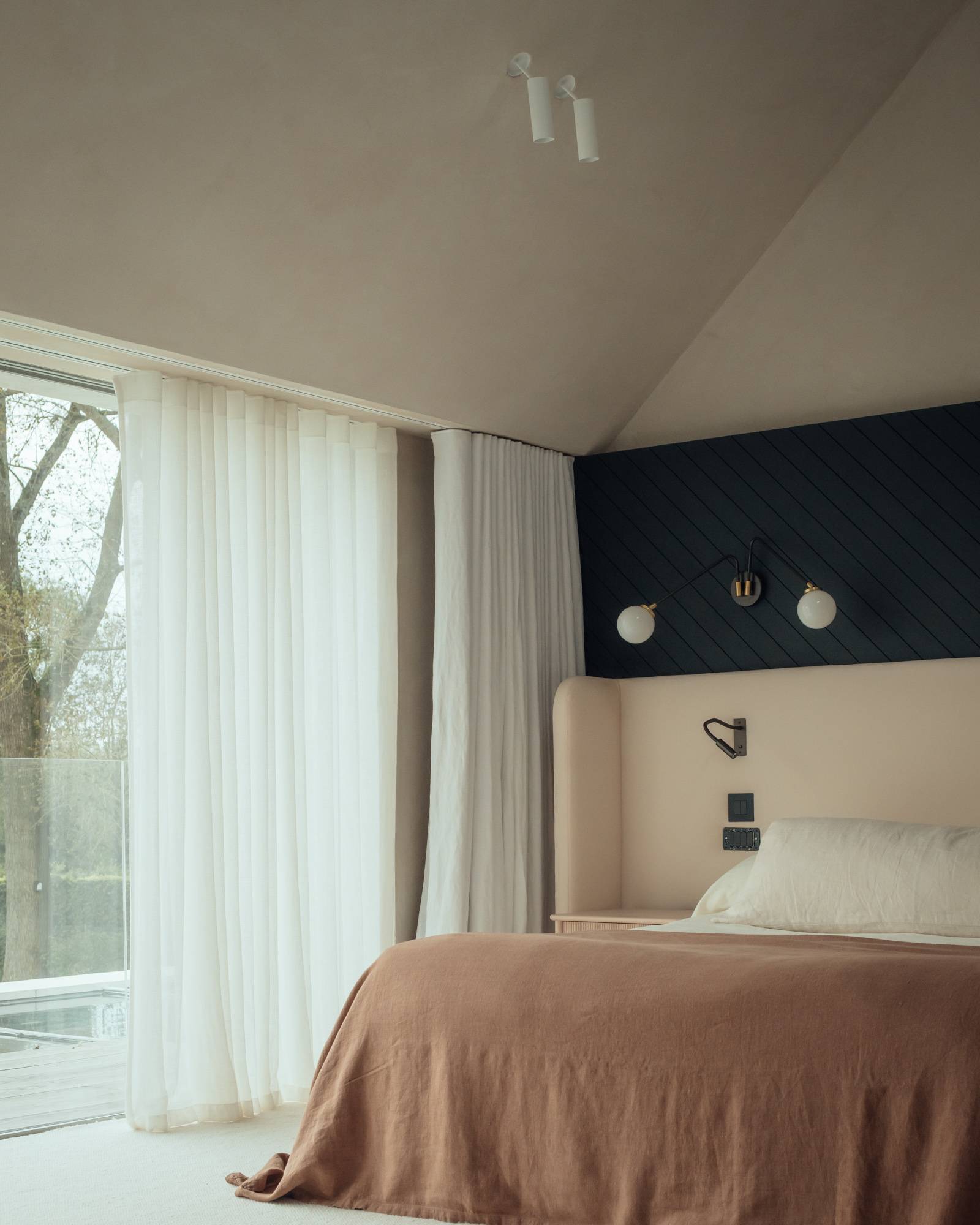 Luxury bedroom setup showing a black fluted feature wall with modern wall sconces and earthy bed linens, ideal for boutique hotel-style campaigns, Love Locations SO20.