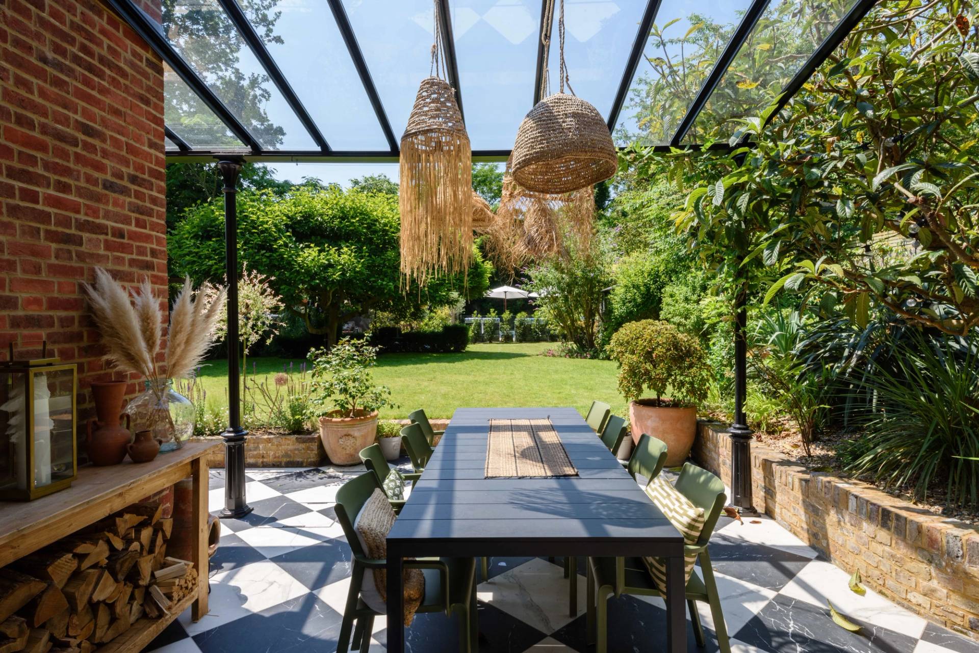Covered outdoor dining space under a timber pergola with long dining table and woven pendant lights, Love Locations TW11.