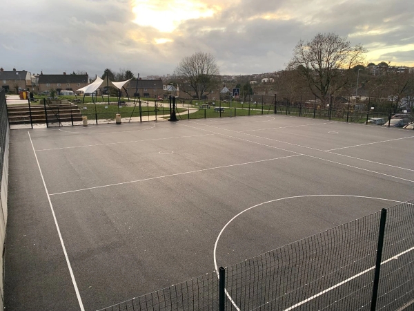 Love Locations outdoor tarmac sports court BS7: Hardstanding all-weather court area with white line markings under a dramatic sky, perfect for urban youth dramas and outdoor fitness photography.