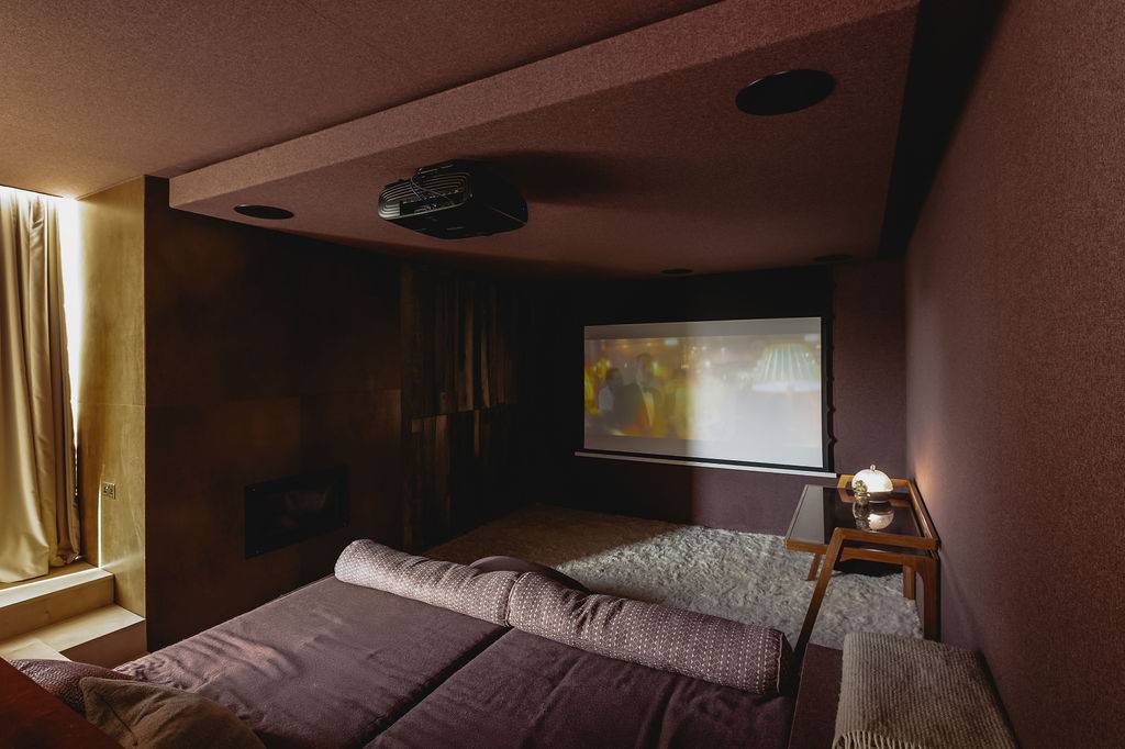 Subterranean home cinema featuring a projection screen, floor cushions, and ambient dim lighting, Love Locations GU32.