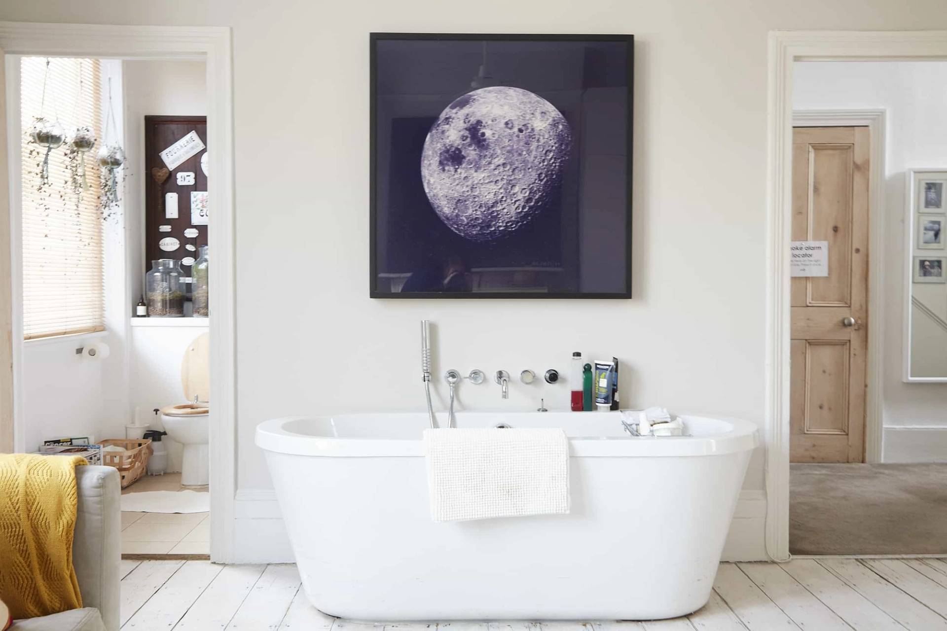 Freestanding white soaking tub set against white painted timber floorboards with a moon artwork print above, ideal for skincare ads, Love Locations N5.