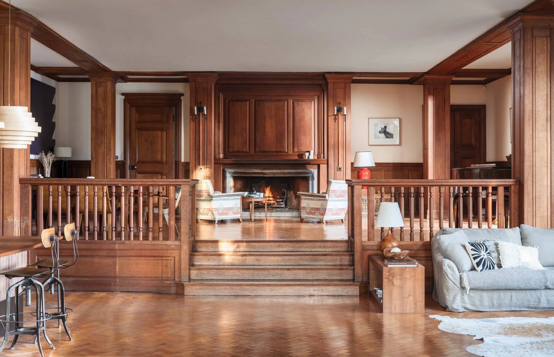 Atmospheric reception hall shoot location in Totnes Devon TQ12 via Love Locations, showcasing a raised grand fireplace nook, wooden stairs, and rich timber panelling.