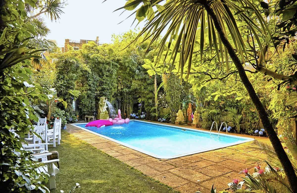 Private outdoor swimming pool surrounded by lush green lawns and palm trees in Kensington and Chelsea, ideal for summer campaign shoots, Love Locations SW5.