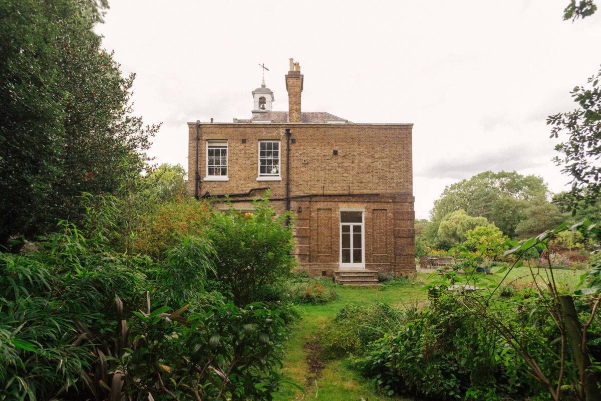 Side exterior elevation of a Georgian house framed by climbing ivy and manicured gardens, Love Locations.