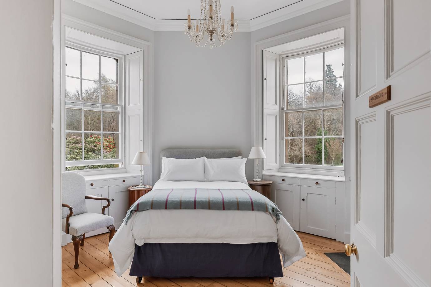 Bright bedroom with grey padded bedframe set between two large sash windows, Love Locations KY15.