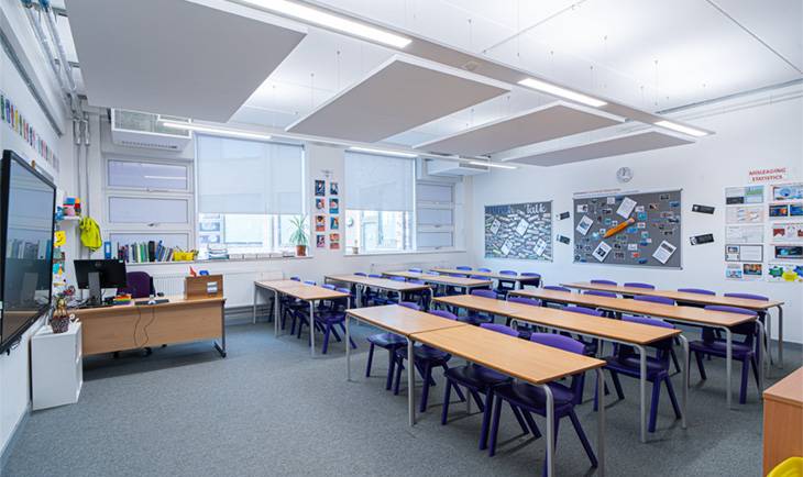 Modern school classroom filming location in Hove BN3 from Love Locations, featuring wooden student desks, blue chairs, whiteboards, and large windows.