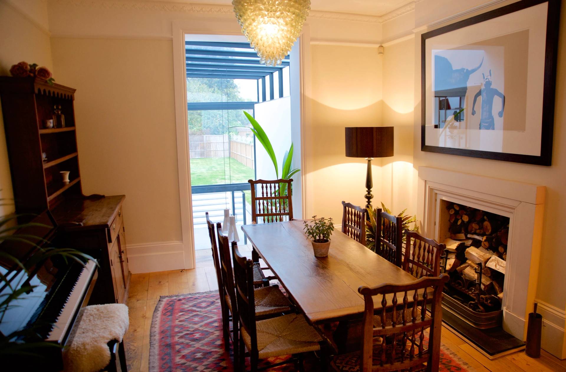 Formal dining room with long wooden table, dark dining chairs, and warm floor lamp lighting, Love Locations TW1.