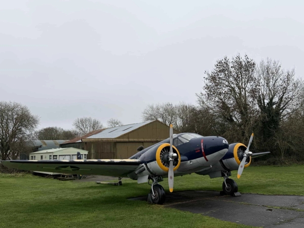 Twin-engine vintage aircraft parked outside an aviation hangar on a historic airfield location in Northamptonshire, Love Locations NN17.