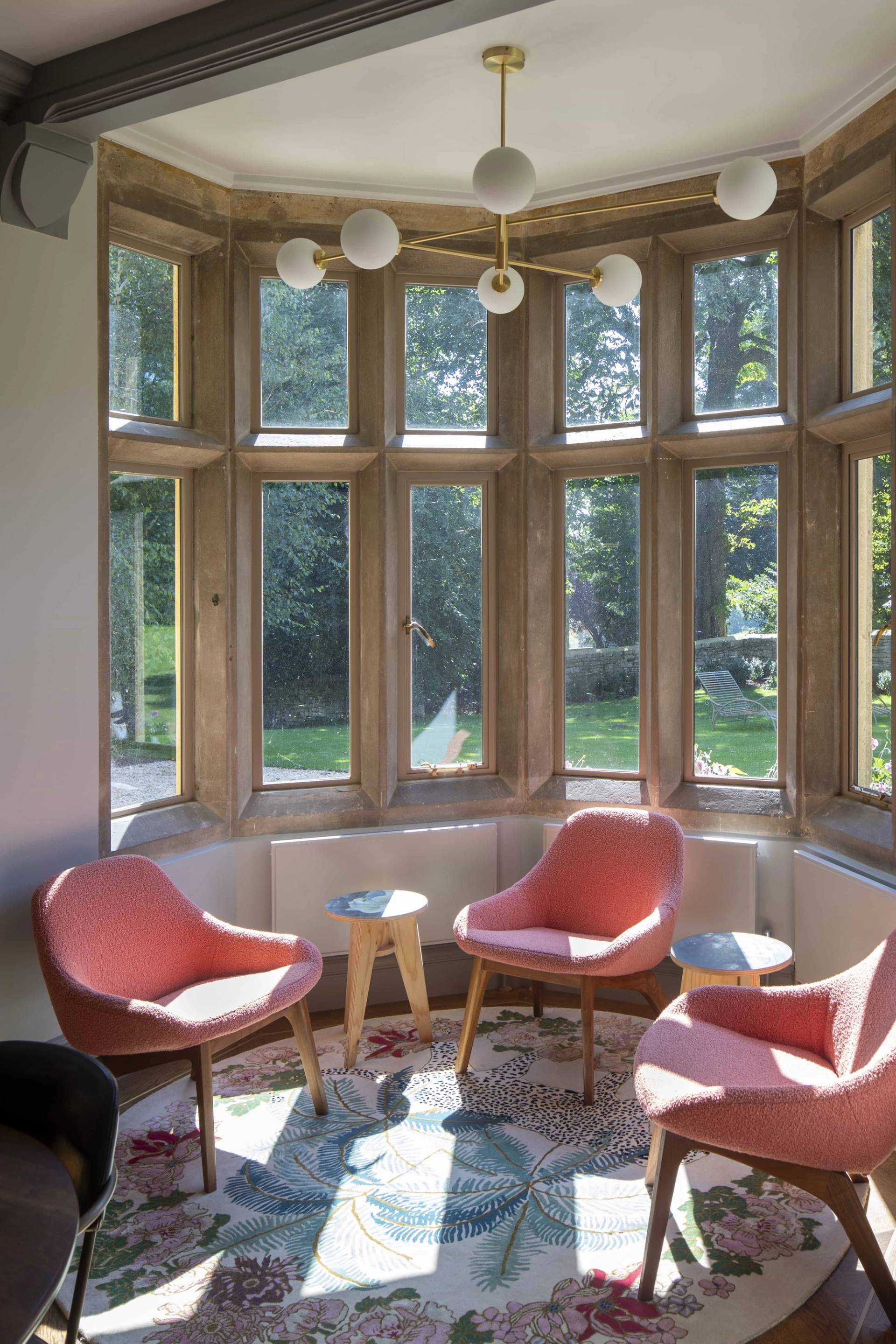 Stone bay window nook in OX7 styled with coral pink lounge armchairs and small coffee tables, Love Locations Oxfordshire.