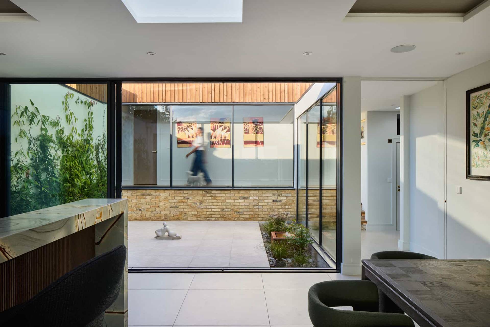 Internal glass atrium courtyard view connecting modern indoor living spaces with natural stone walls, ideal for architectural photography, Love Locations.