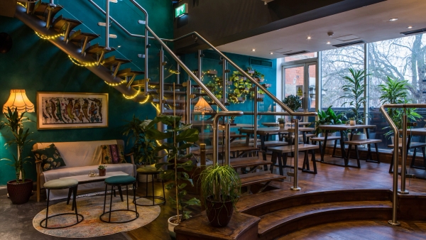 Iconic venue shoot location at the Ritzy Picturehouse in Brixton, SW2 featuring a open stairwell with metal handrails, timber steps, and lush indoor plants, ideal for indie film scenes via Love Locations.