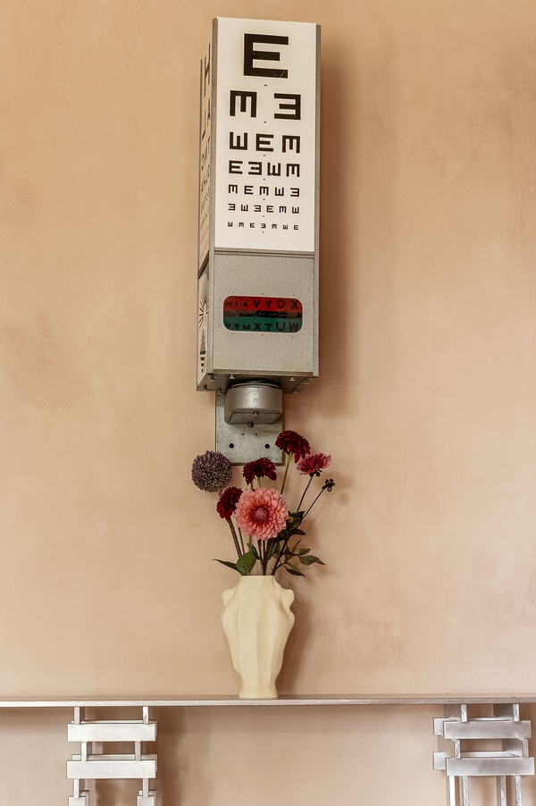 Vintage eye test chart prop hung against a raw, distressed plaster wall surface, a unique editorial backdrop from Love Locations.