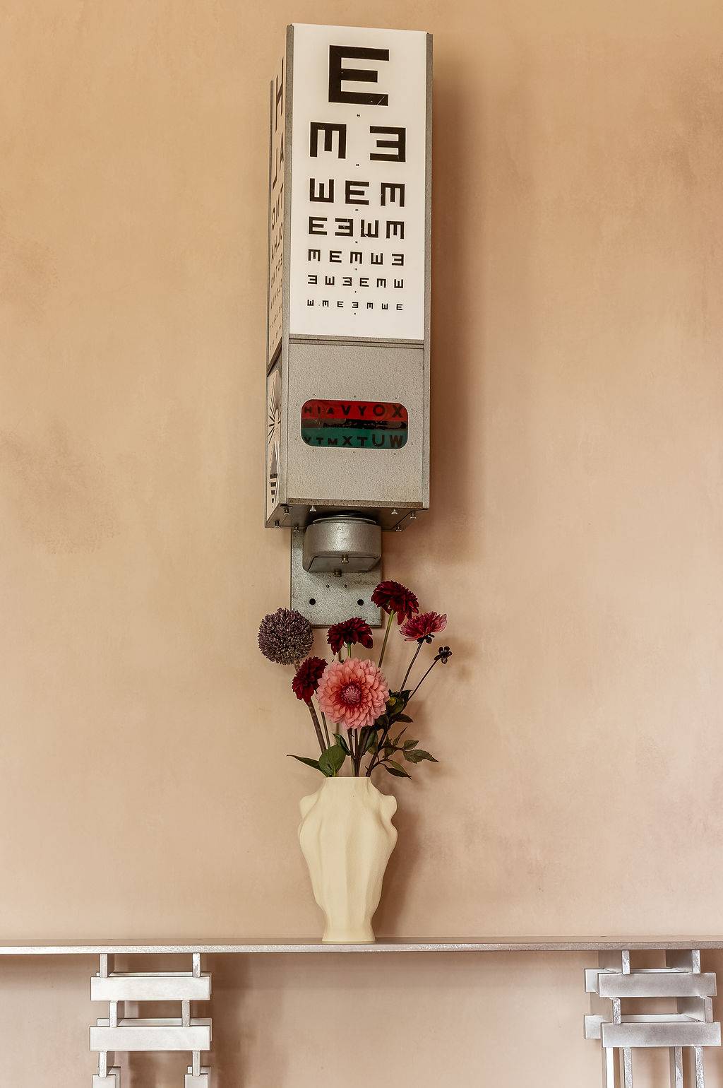 Vintage eye test chart prop hung against a raw, distressed plaster wall surface, a unique editorial backdrop from Love Locations.