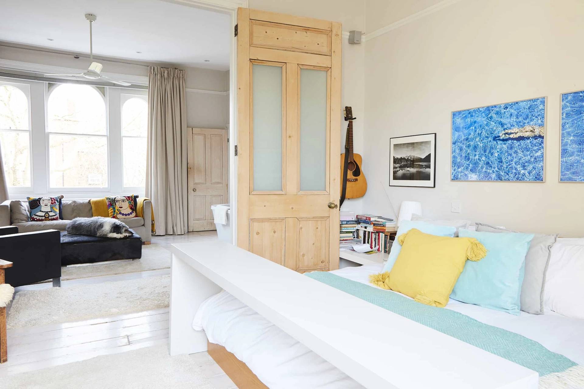 Master bedroom detail showing a low wooden bed set before an original stripped pine door transition, Love Locations N5.