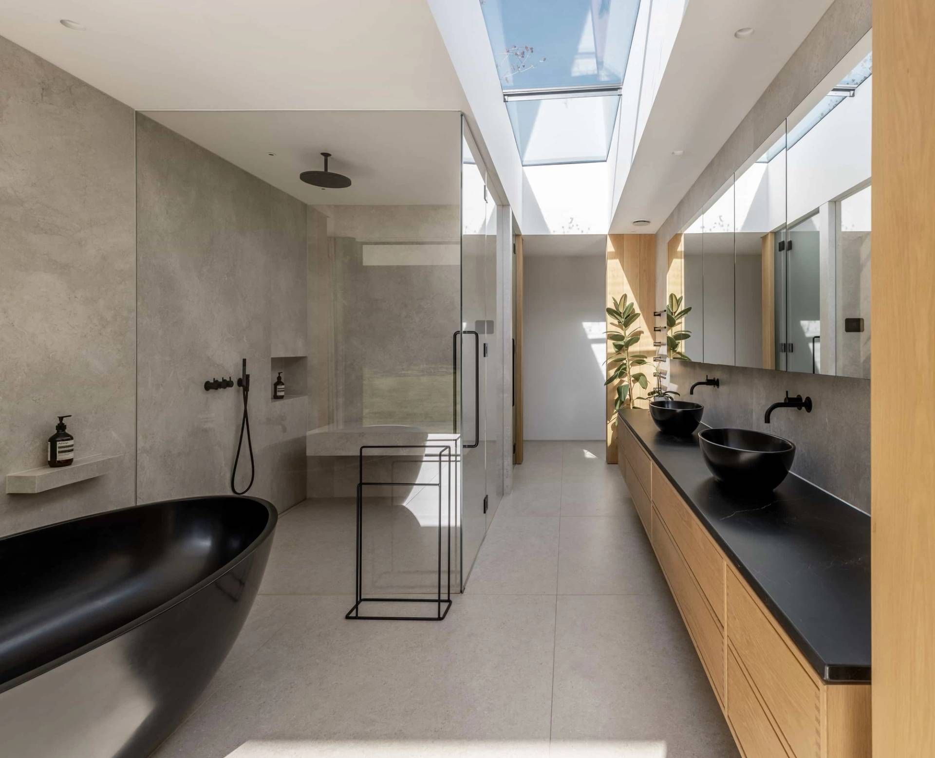 Luxury contemporary bathroom featuring a freestanding black bathtub, walk-in glass shower, double timber vanity, and overhead skylights, Love Locations CM4.