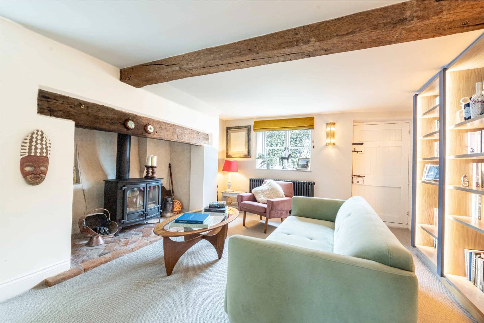 Cozy reception lounge featuring exposed ceiling beams, wood-burning stove, and pale green sofa, Love Locations GU28.