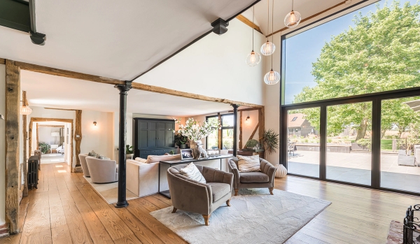 Vaulted ceiling barn location hall with exposed timber beams and elegant cream armchairs for television shoots, Love Locations.