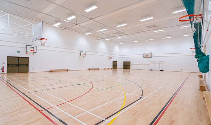 Indoor sports hall filming location in Hove BN3 featuring court line markings, basketball hoops, and light wood flooring via Love Locations.
