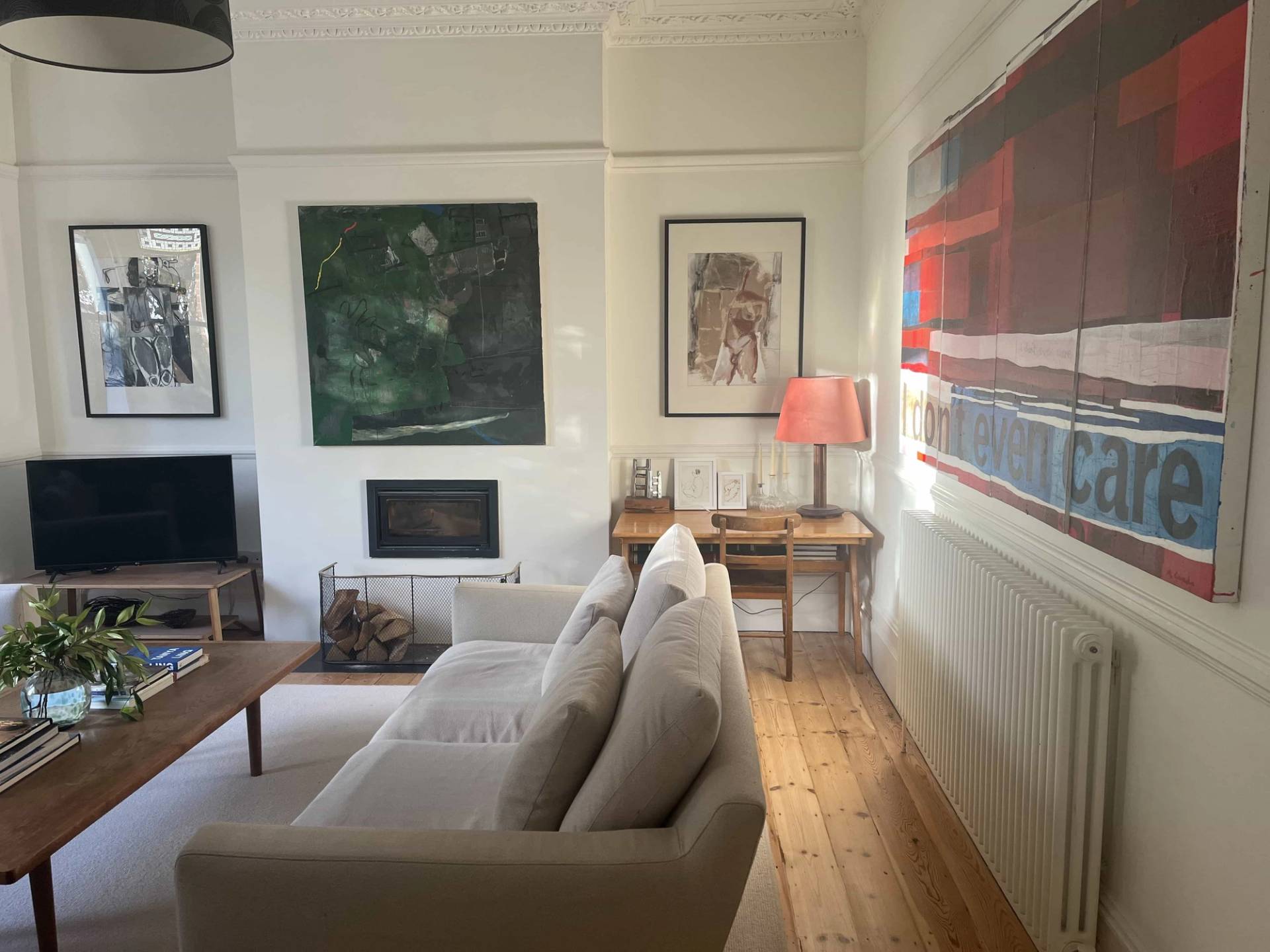 Spacious living room in South Camberwell, SE5 with beige sofas, stripped timber floorboards, and contemporary art wall displays, Love Locations SE5.