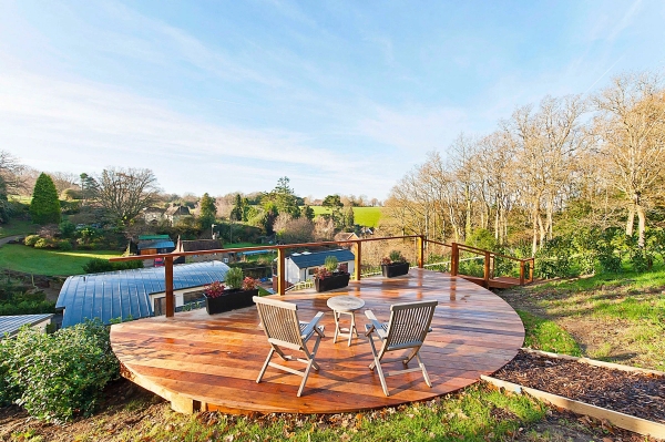Circular viewing deck terrace equipped with retro metal garden chairs overlooking a panoramic tree-lined valley landscape, Love Locations.