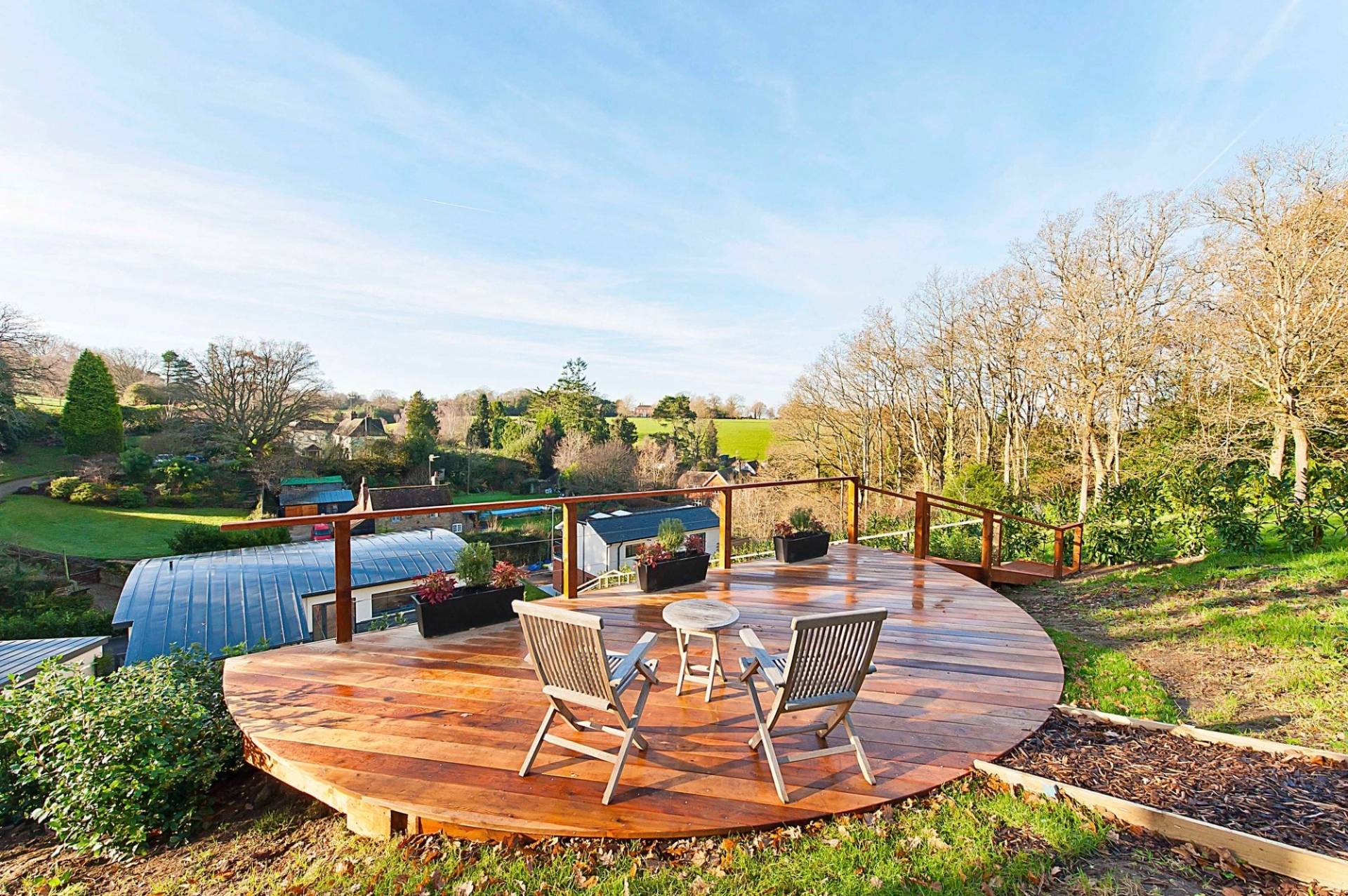 Circular viewing deck terrace equipped with retro metal garden chairs overlooking a panoramic tree-lined valley landscape, Love Locations.