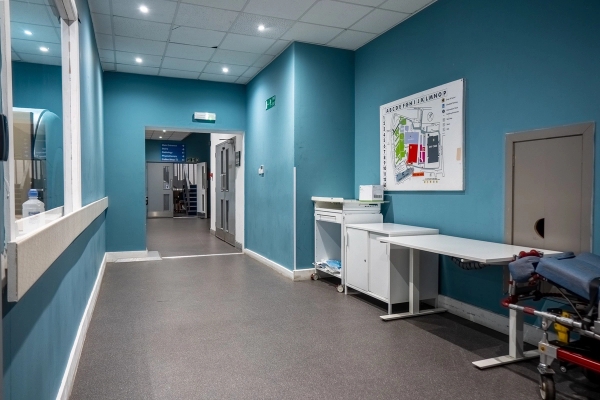 Hospital hallway corridor with blue walls, medical storage cabinets, and notice boards, Love Locations UB4.