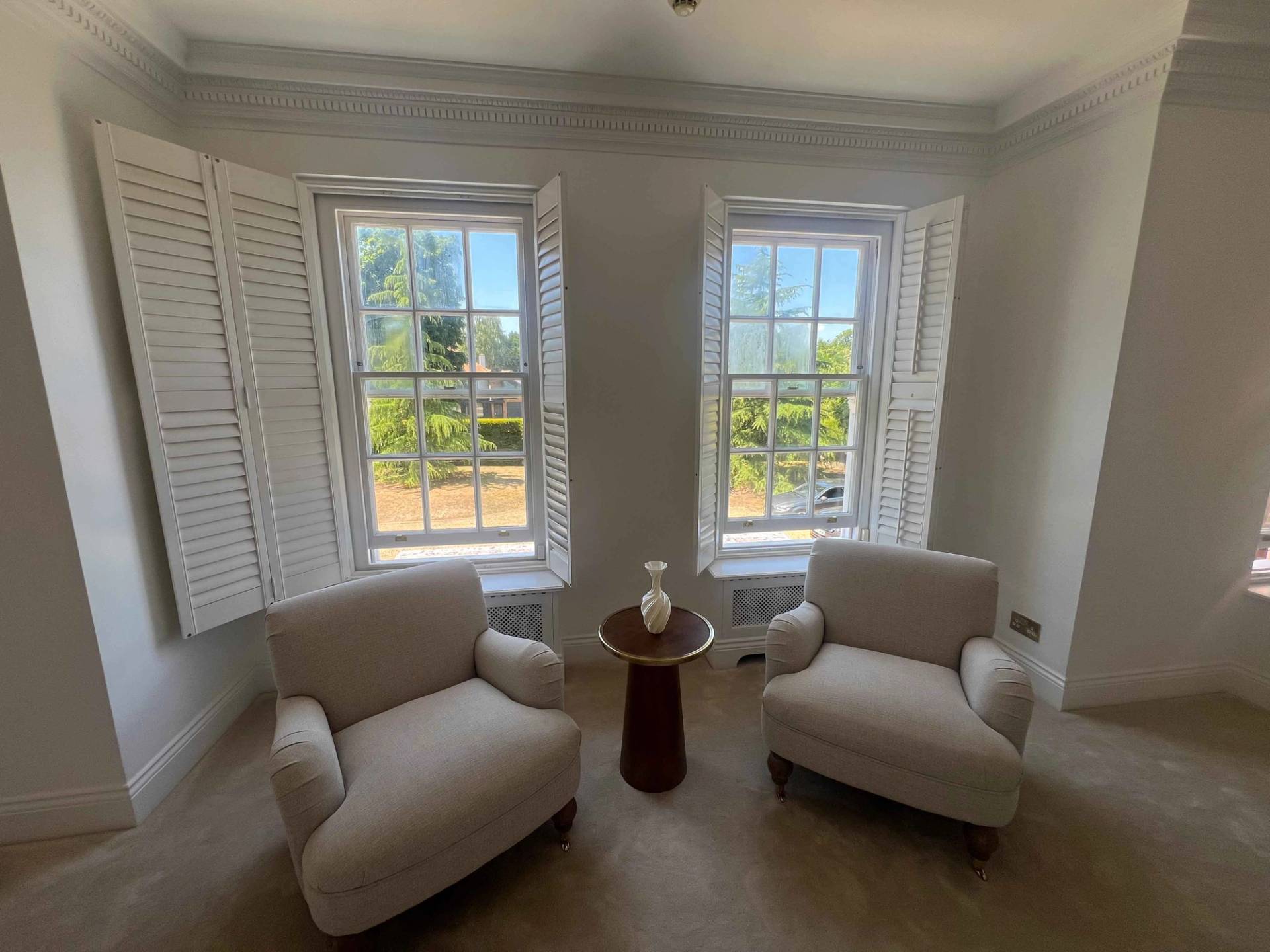 Sitting nook on a upper landing with two armchairs set beside double sash windows and shutters, Love Locations BR7.