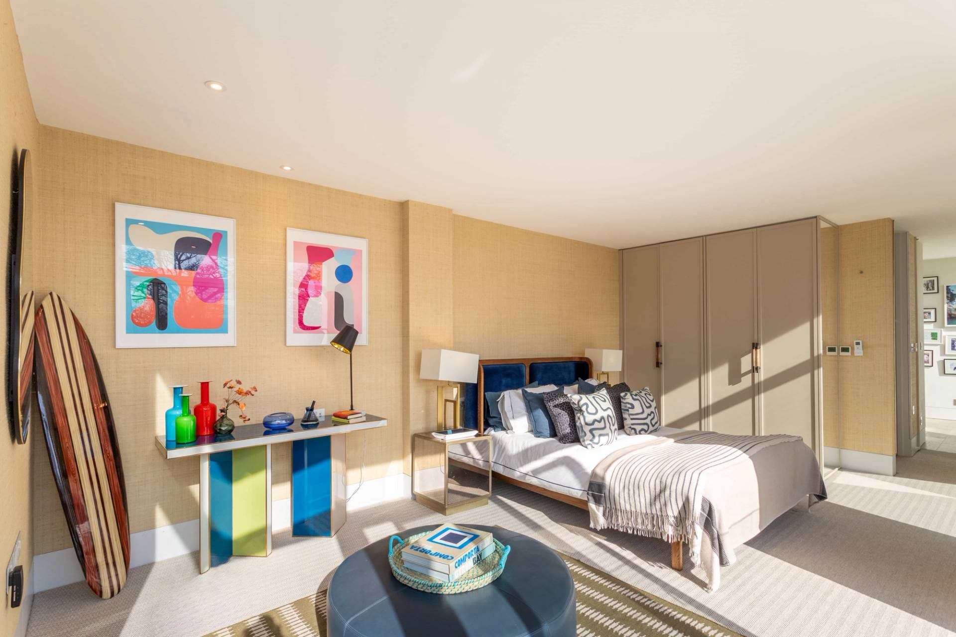Love Locations modern property location GU8: Bedroom view showing bright afternoon light streaming in through a full-height glass door leading directly out to a stone patio.
