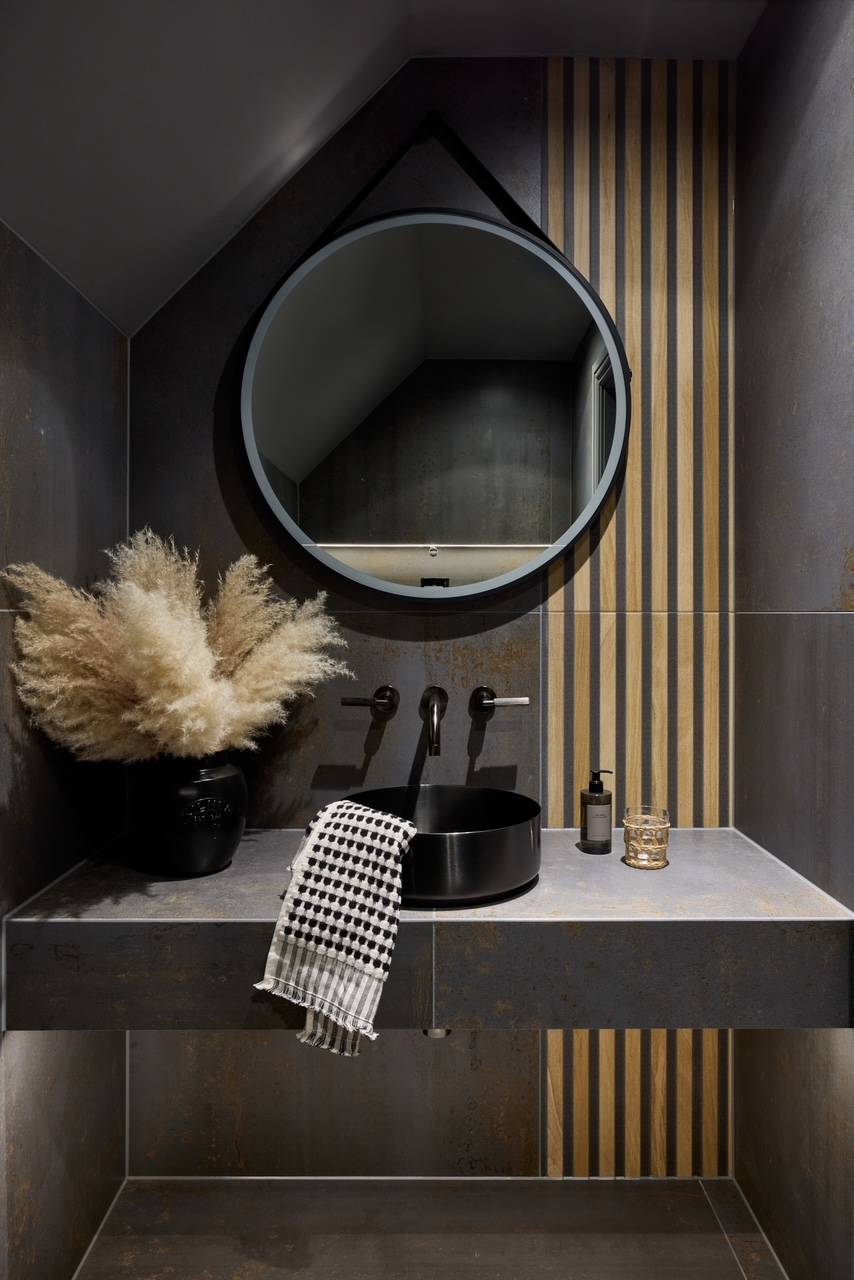 Dark dramatic cloakroom toilet featuring vertical timber slats and a matte black stone vanity setup, perfect for moody luxury product photography, Love Locations.